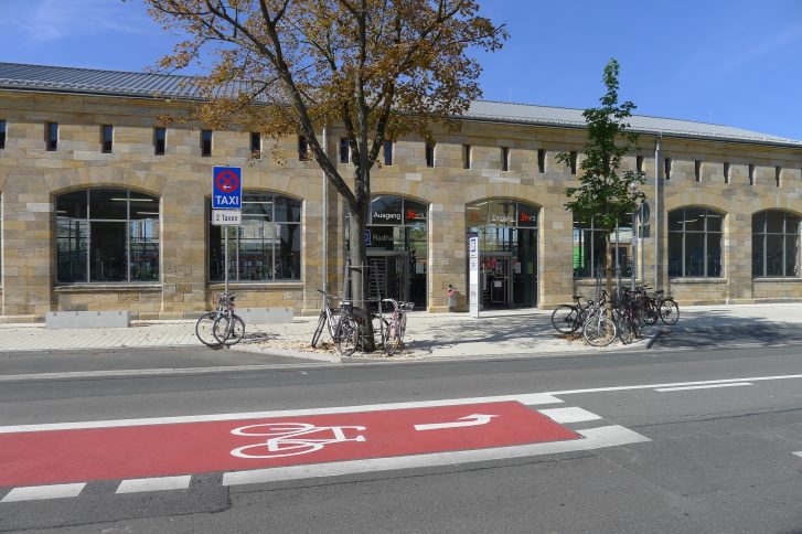 Historisches Sandsteingebäude, das die Fahrradgarage beherbegrt,  mit großen Fenstern und den Schildern 