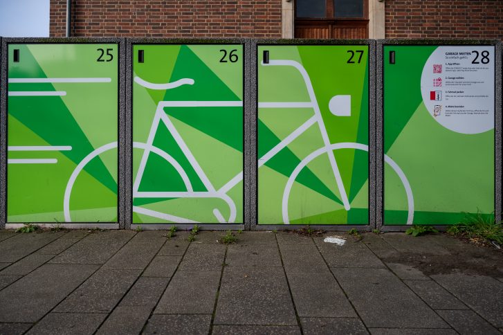 Fahrradboxen vor dem Fahrradparkhaus mit Fahrrad-Logo in grün