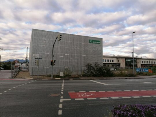 Aussenansicht des quadratischen Fahrradparkhaus über eine Straßenkreuzung hinweg