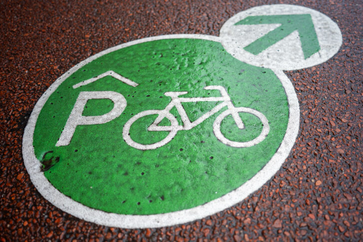 Grüne Bodenmarkierung mit Fahrrad(parkhaus)-Emblem und Pfeil