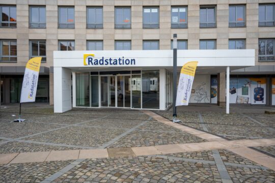 Eingag Radstation. Weiße automatische Schiebetüren führen ins Gebäude.