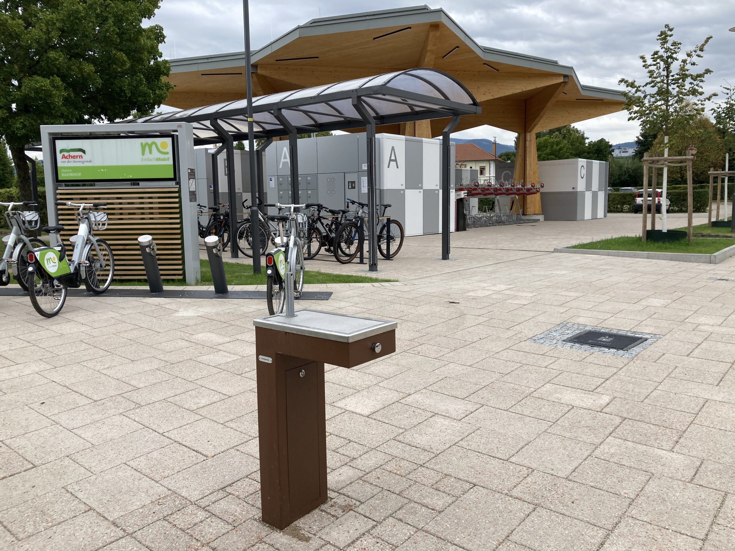 Mobilitätsstation und offenes Fahrradparkhaus am Bahnhofsvorplatz; Getränkespender, Leihahrräder und Fahrradboxen sowie Doppelstockparker sind sichtbar