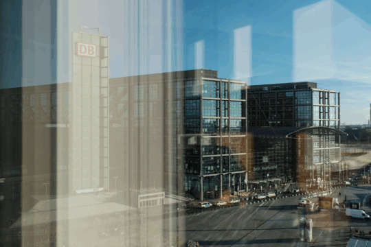 Blick durch ein Fenster auf den Vorplatz des Berliner Hauptbahnhofs im Sonnenschein